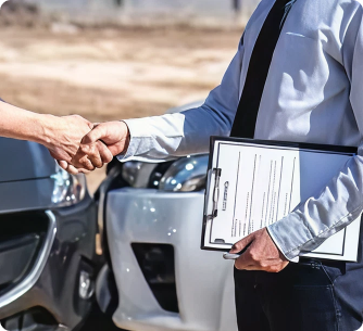 A handshake between an insurance adjuster and a driver at a car accident scene.