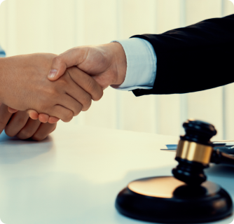 A close-up of two people shaking hands over a desk with a judge's gavel in the foreground.