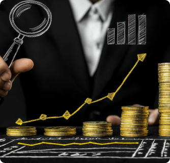 A businessman in a dark suit standing behind a chalkboard featuring a hand-drawn gold growth chart. Stacks of gold coins increase in height along the rising arrow, with a magnifying glass hovering nearby.