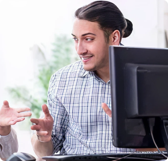 A smiling man in a plaid shirt gesturing during a conversation in an office setting.