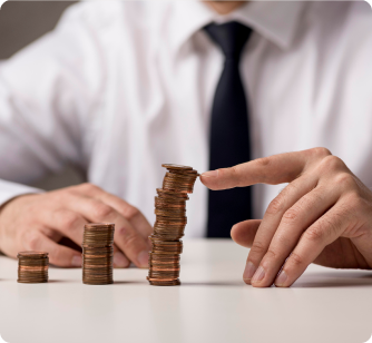 A person in a white shirt and black tie uses a finger to adjust a stack of copper coins on a white table.