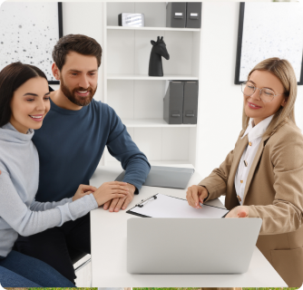 female consultant smiles while showing a laptop screen to a young couple in a bright office.