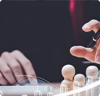 A person’s hand carefully places a small wooden figure among other figures on a desk, with glowing digital interface lines in the foreground, suggesting strategy or decision-making.