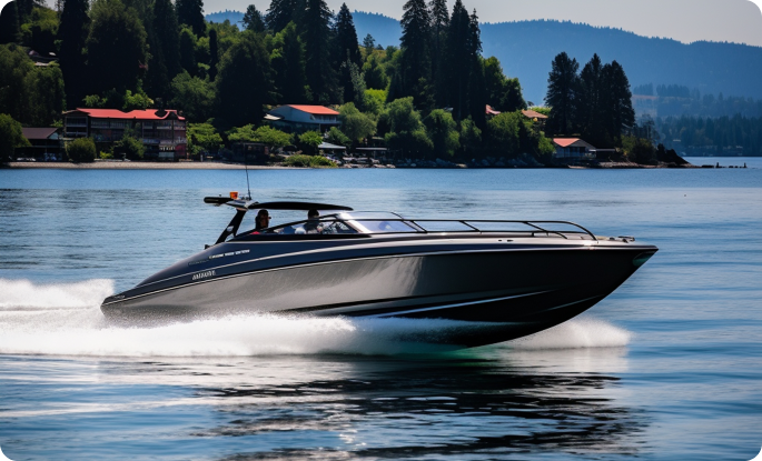 A sleek, dark grey speedboat cruising rapidly across a calm lake backed by evergreen trees.