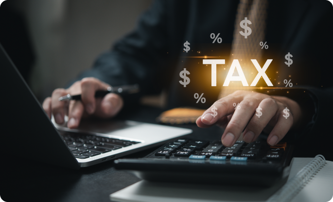 A person uses a calculator and laptop with glowing "TAX," dollar sign, and percentage symbols overlaying the scene.