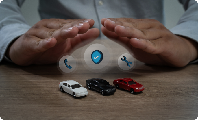 A person’s hands form a protective arch over three toy cars, accompanied by floating icons for a shield, phone, and wrench.